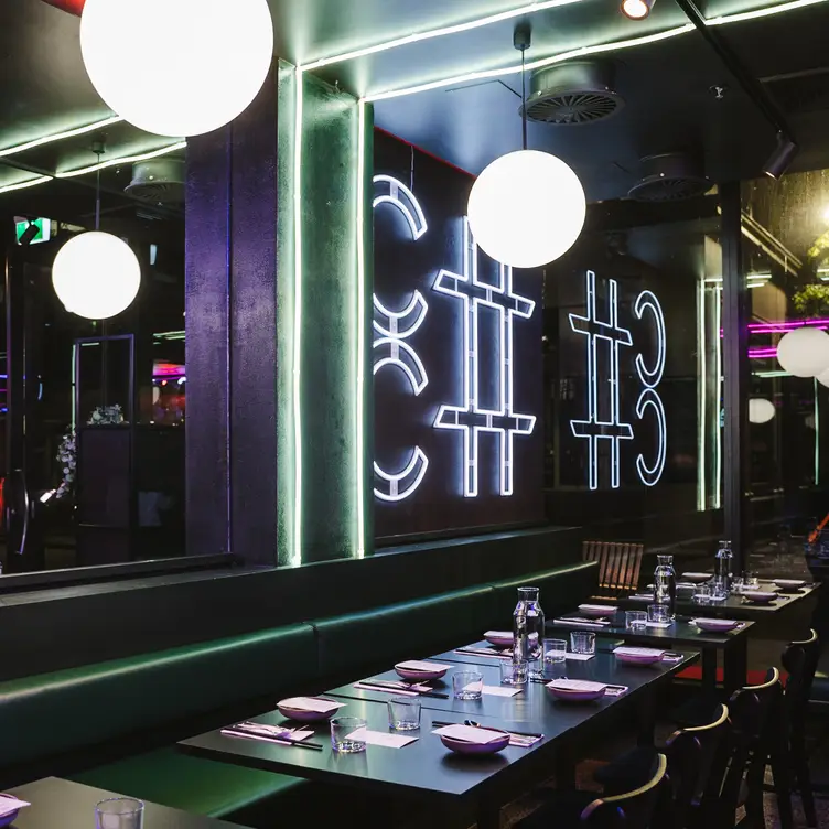 The interior of Cha Ching, with neon lights and writing along the walls and ceiling.