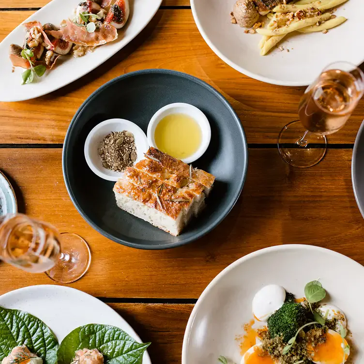 A number of dishes including soft bread, eggs and salad served alongside flutes of wine at Trofeo Estate, one of the best winery restaurants in Victoria.