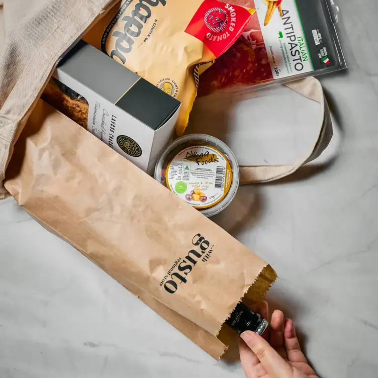 A cloth bag filled with cured meats, crackers, olives and a wine bottle from With Gusto Regional Store, one of the best new restaurants in Melbourne in 2024.