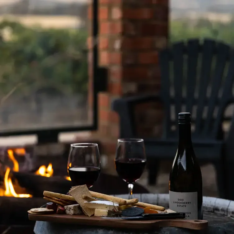 Two glasses of wine and a delicious cheese board in front of the fire at Cleveland Winery, one of the best winery restaurants in Victoria.