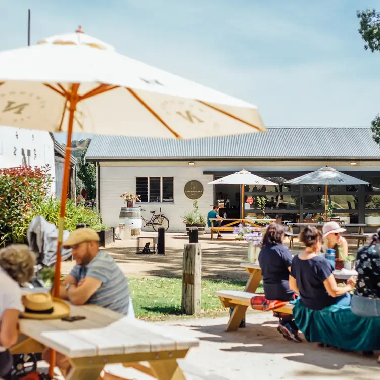 Bench seating, an umbrella and flowers at the outdoor seating area of Kitchen Farm, one of the best regional restaurants in Australia.