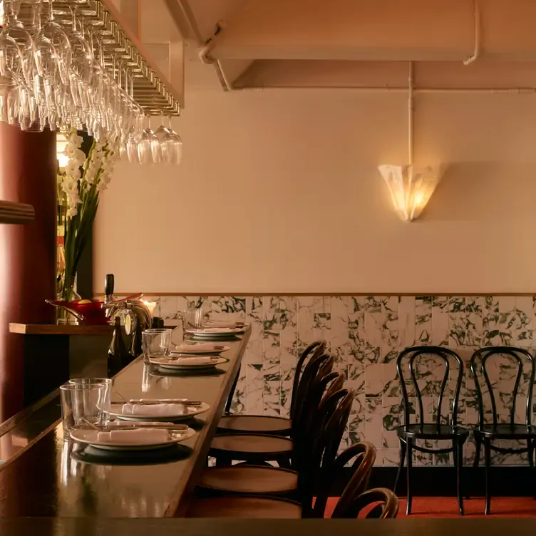 The warmly lit bar lined with seats at the counter and wine glasses hanging from a ceiling rack at Fontana.