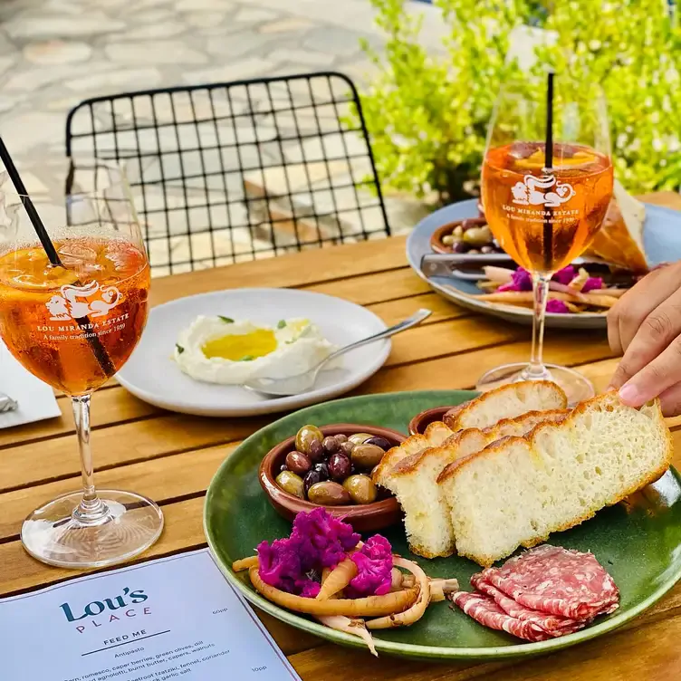 Bread, olives and meat are served alongside large orange drinks at an outdoor table at Lou’s Place, one of the best regional restaurants in Australia.