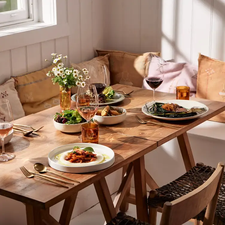 A table laid with several dishes and glasses of red wine and rosé at Down The Rabbit Hole Wines, one of the best regional restaurants in Australia.