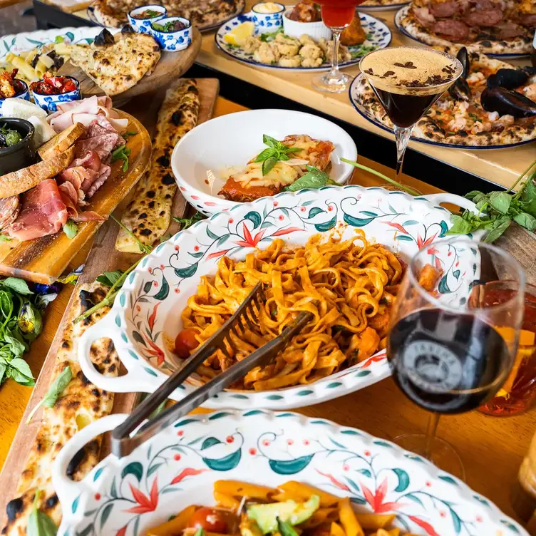 Several dishes, including a bowl of pasta, a plate of cured meat and pizzas, served alongside wine and cocktails at Farina Pizzeria - Top Ryde.