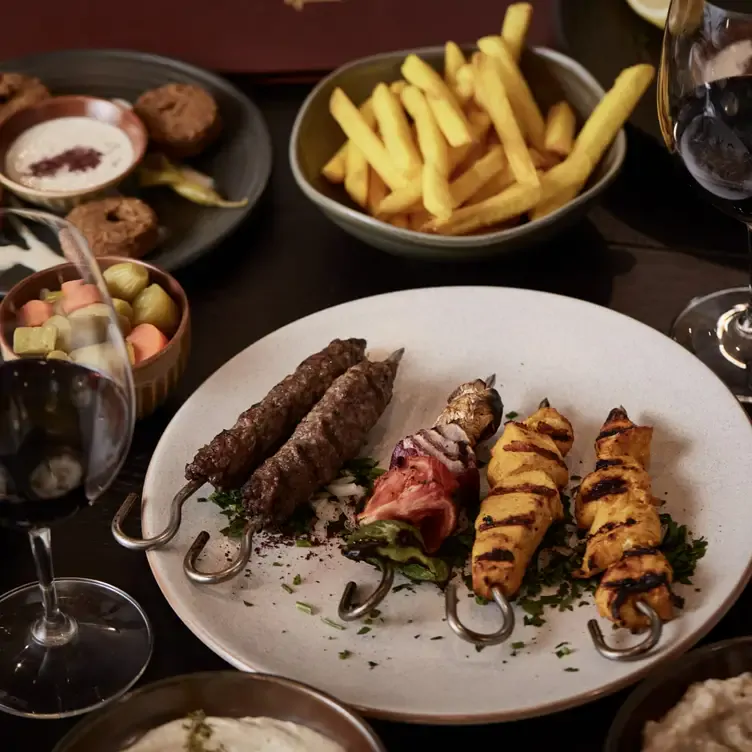 A plate of skewers and a bowl of chips served among other dishes at Sherwal.