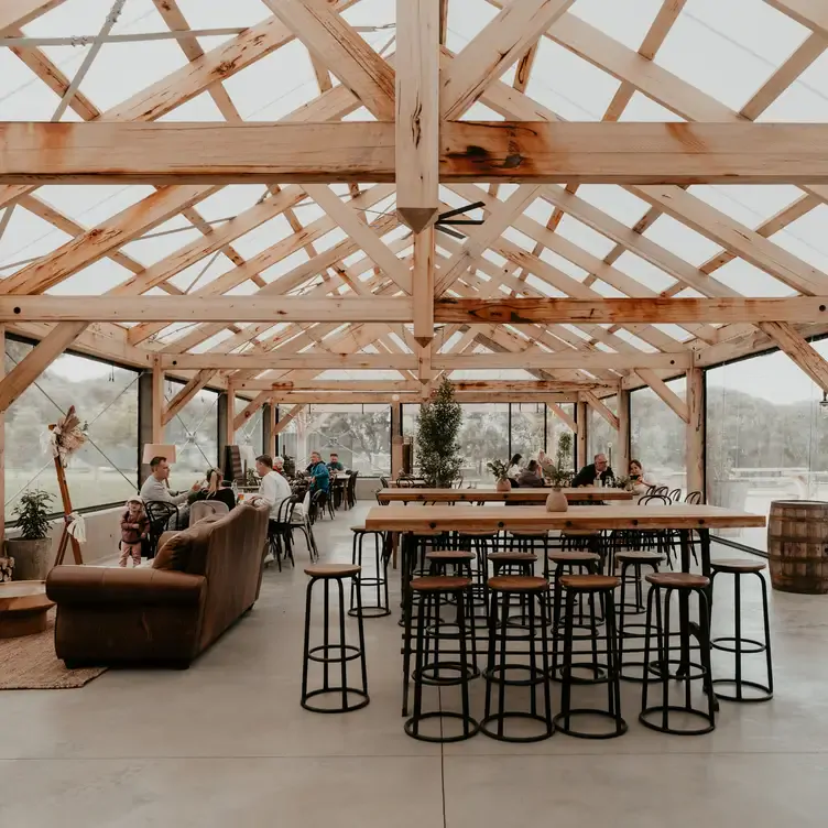 The interior of Phillip Island Winery’s greenhouse-style dining space with exposed beams and see-through walls.