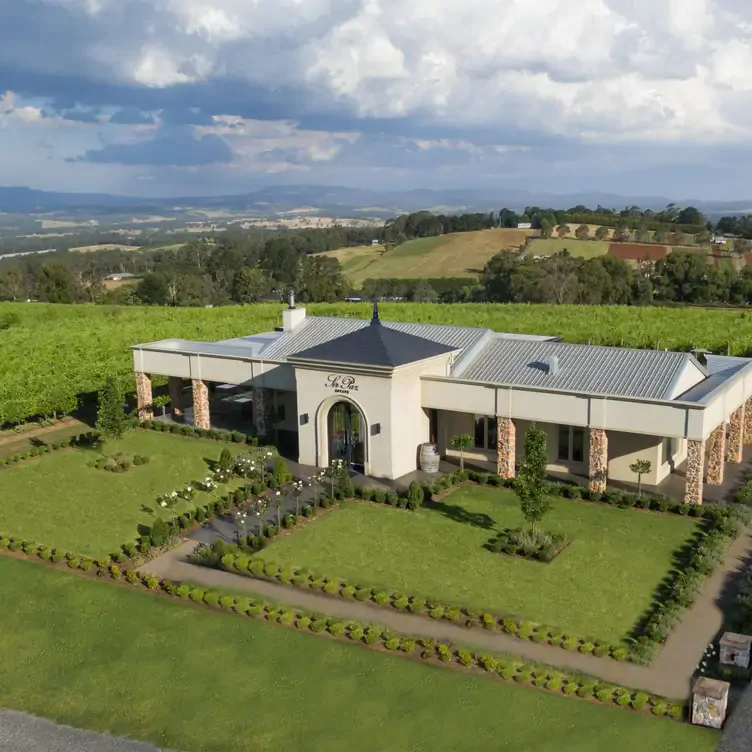 The exterior of Sir Paz Estate, one of the best winery restaurants in Victoria, showing its white walls and manicured lawn lined with bushes.