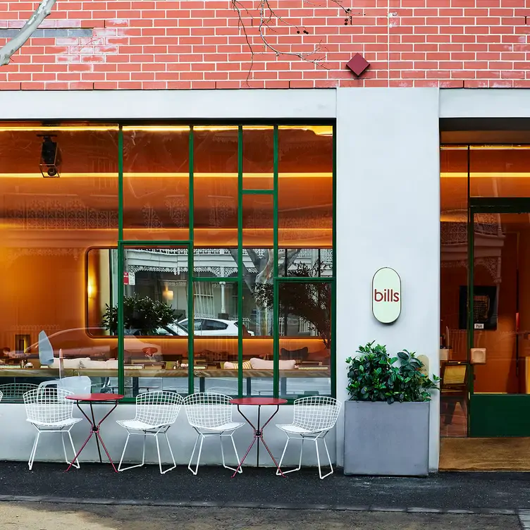 The exterior of bills, one of Sydney’s best new restaurants on OpenTable, with metal chairs and tables in front of large windows that look into the restaurant.