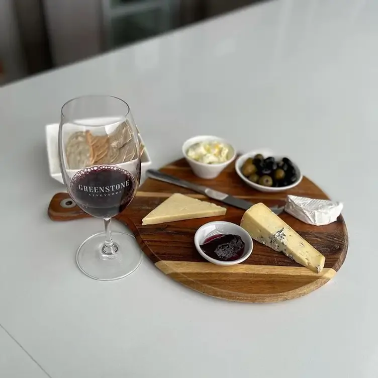 A glass of wine and a plate of cheese, biscuits and olives from Greenstone Vineyards, one of the best wineries in Victoria.