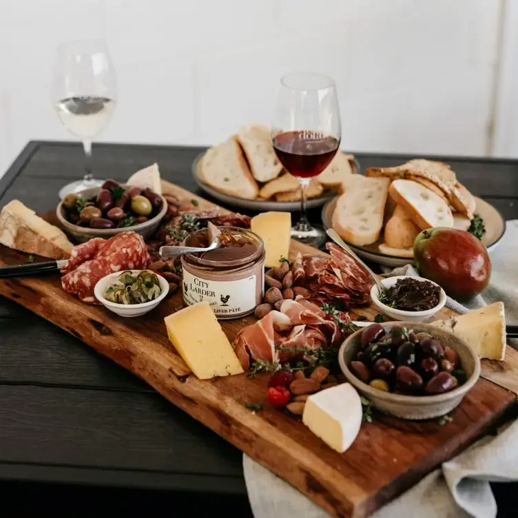 Plates of bread and a board filled with salami, prosciutto, bowls of olives and cheese at Rob Dolan Wines.