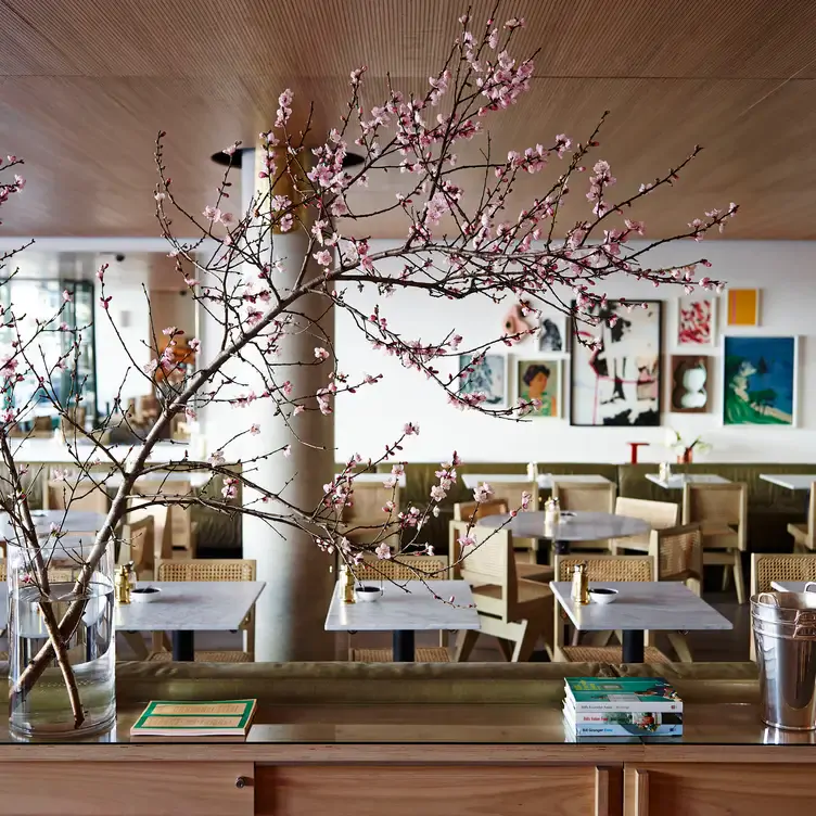 The interior of Bills with cherry blossom branches in the foreground and several white tables with straw chairs in the background.