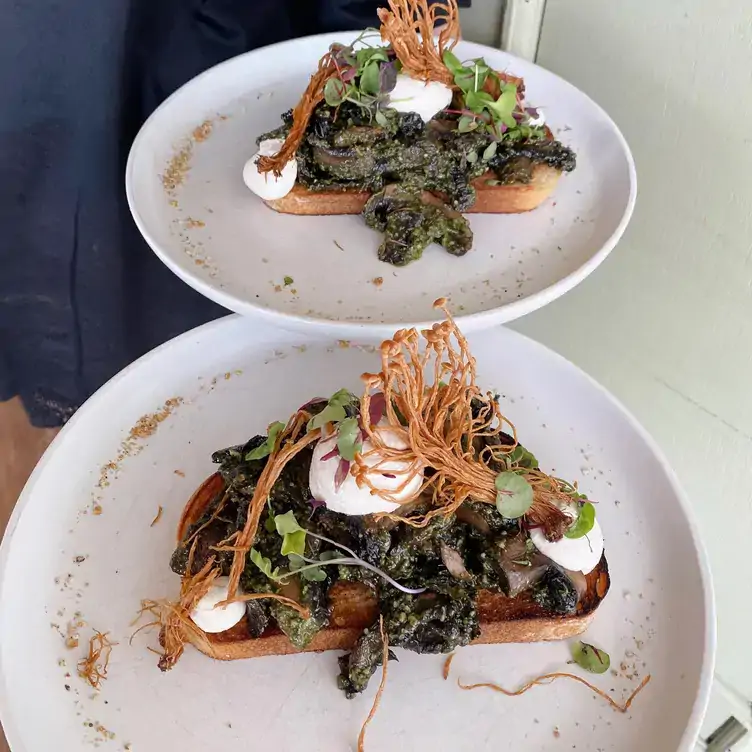 Two plates of toast topped with veggies at Plant Vibes Cafe, one of the best places for brunch in Brisbane.