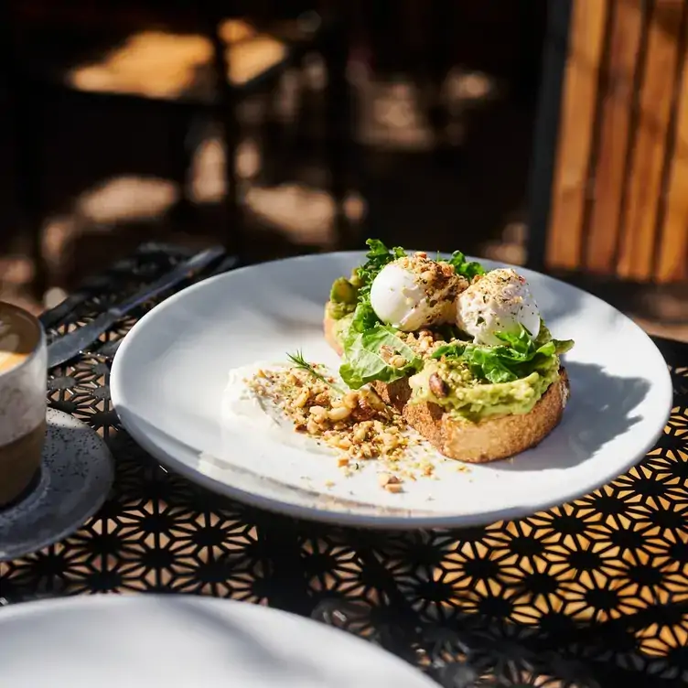 A plate with avocado and poached eggs on toast served at Two Before Ten, one of the best brunch spots in Canberra.