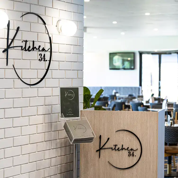 The host stand at Kitchen 34, showing the logo on the wall and menus in front of the stand.