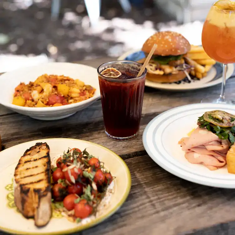 A table with several dishes, including a burger and a salad served alongside drinks, at Peter Rabbit, one of the best family restaurants in Adelaide.