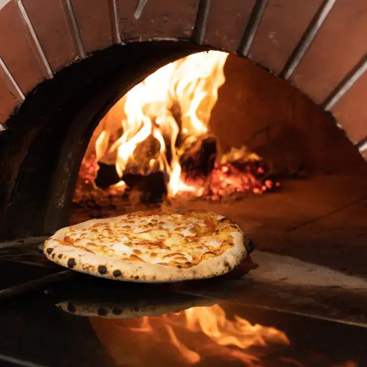 A pizza being taken out of a wood-fire pizza oven at Ms Peacock, one of the best family restaurants in Melbourne.