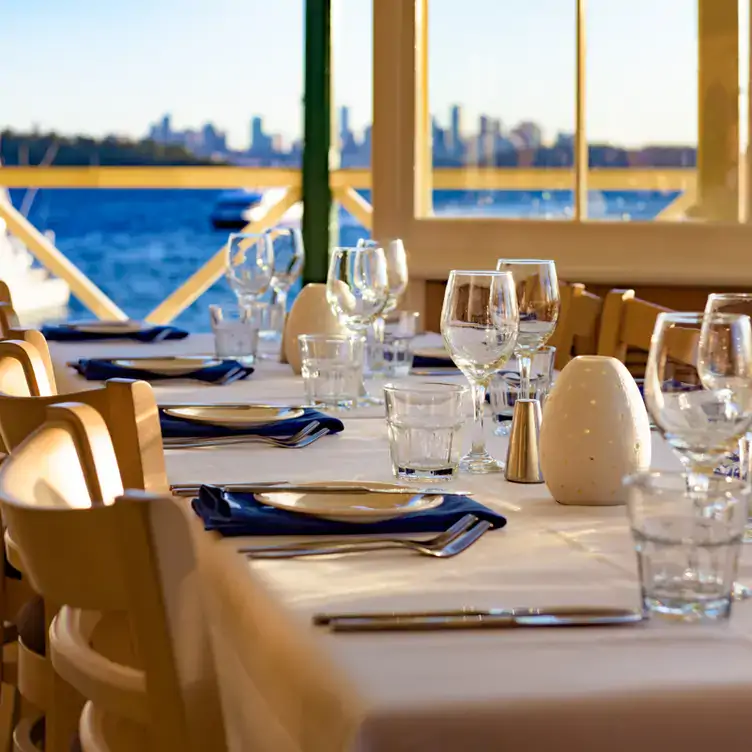 A long indoor table with a cream tablecloth and deep-blue napkins at Doyles on the Beach, one of the best family restaurants in Sydney.