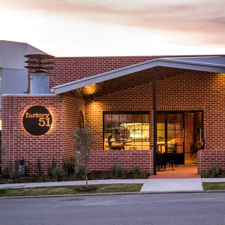 The red-bricked exterior of Factory51, showing the warm lighting coming from its interior.