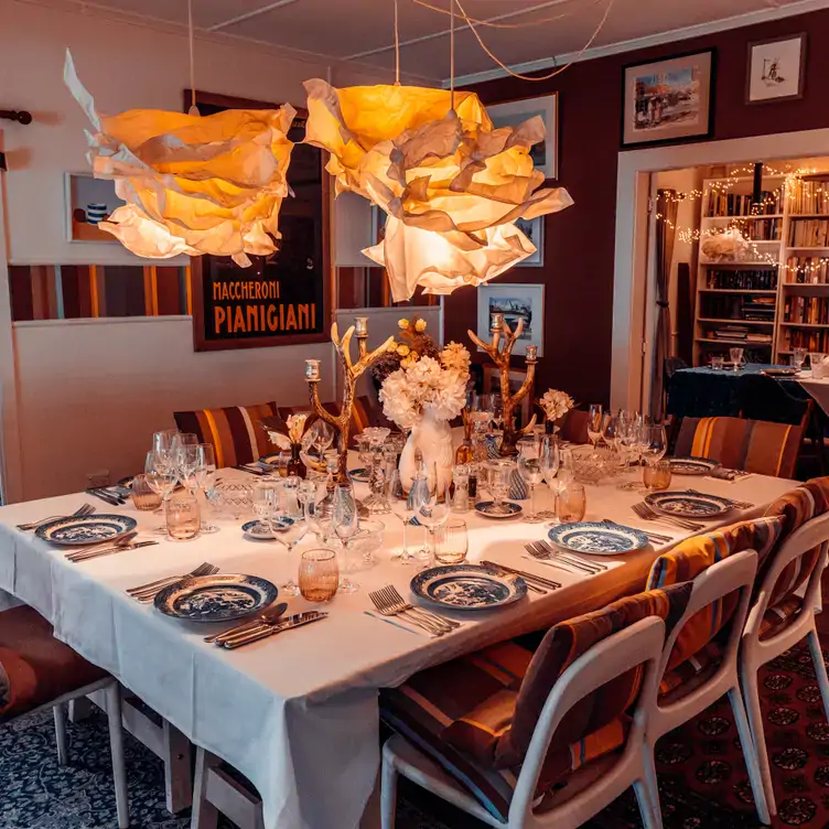 A large square dining table set for brunch with striped chairs at Bumbles Cafe.