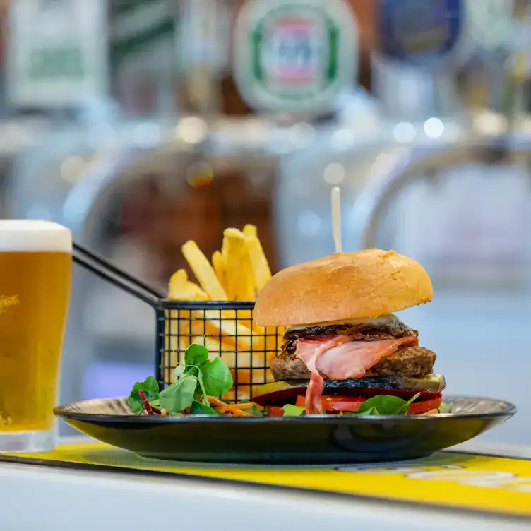 A burger served alongside salad, chips and a glass of beer at Sails Restaurant, Redlands RSL.