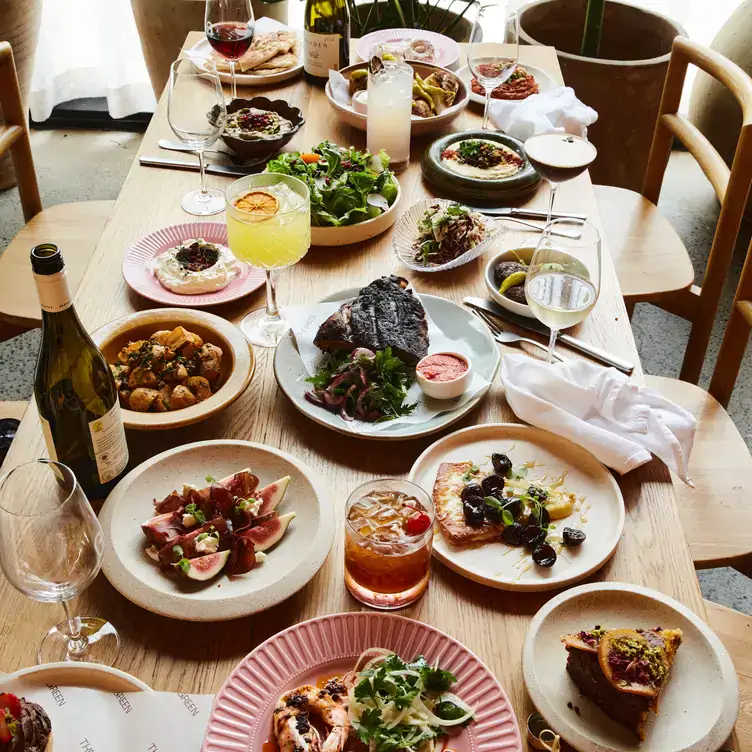 A long table laid with several dishes, including pizza and figs alongside drinks, at The Green, one of the best places for brunch in Brisbane.