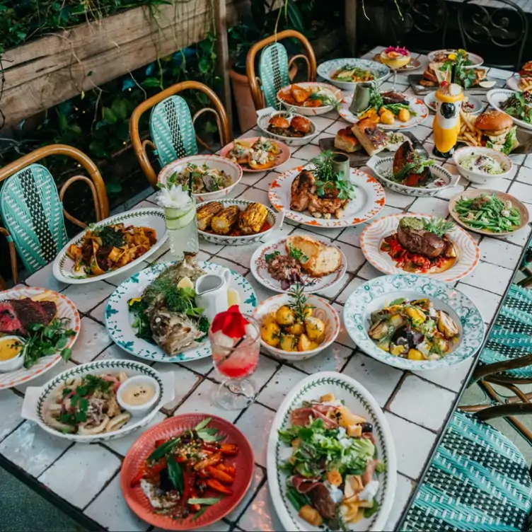 A table packed with dishes, including grilled corn cobs, steaks and pastas, at The Potting Shed, one of the best family restaurants in Sydney.