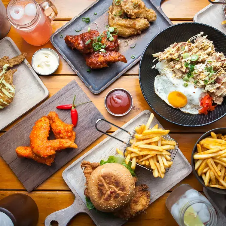 Multiple dishes, including various fried chicken wings, burgers and chips, served at Seoul Bistro, one of the best family restaurants in Brisbane.