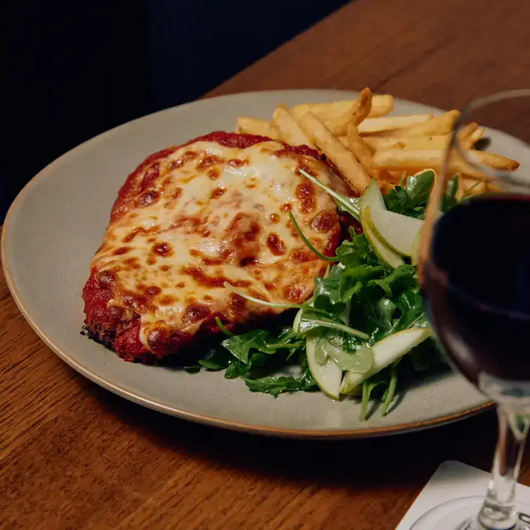 A dish of chicken parma, chips and salad with a glass of red wine at Grandview Hotel, one of the best family restaurants in Melbourne.