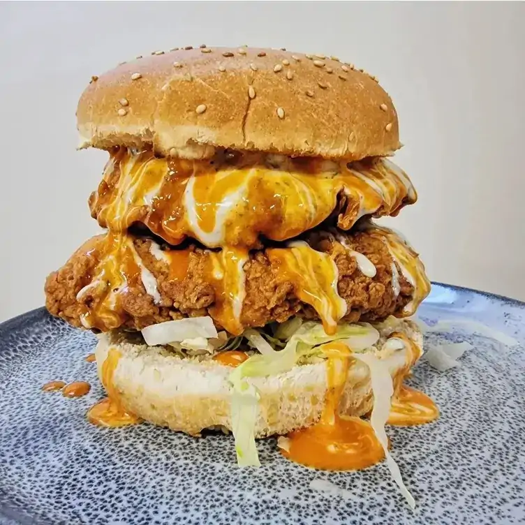 A burger with two pieces of fried ‘chicken’ served at Two-Bit Villains, one of the best family restaurants in Adelaide.