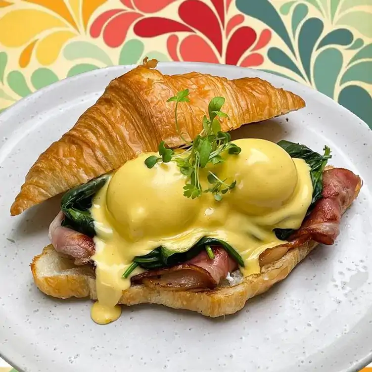 A croissant filled with poached eggs, bacon and spinach, topped with hollandaise sauce, served at My Mistress, one of the best brunch spots in Brisbane.