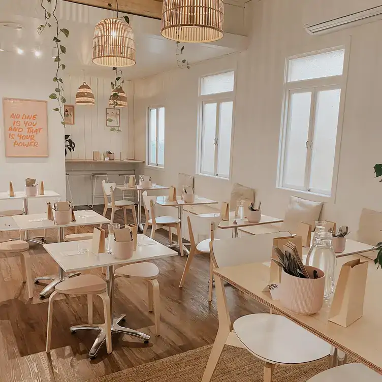 The interior of Plant Vibes Cafe, showing the pale, pastel design, hanging plants and warm lighting.