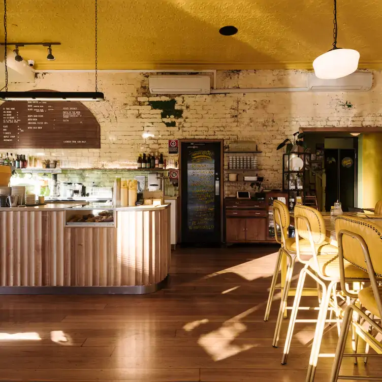 The interior of Happyfield, showing the tall chairs, front counter and exposed brick wall.