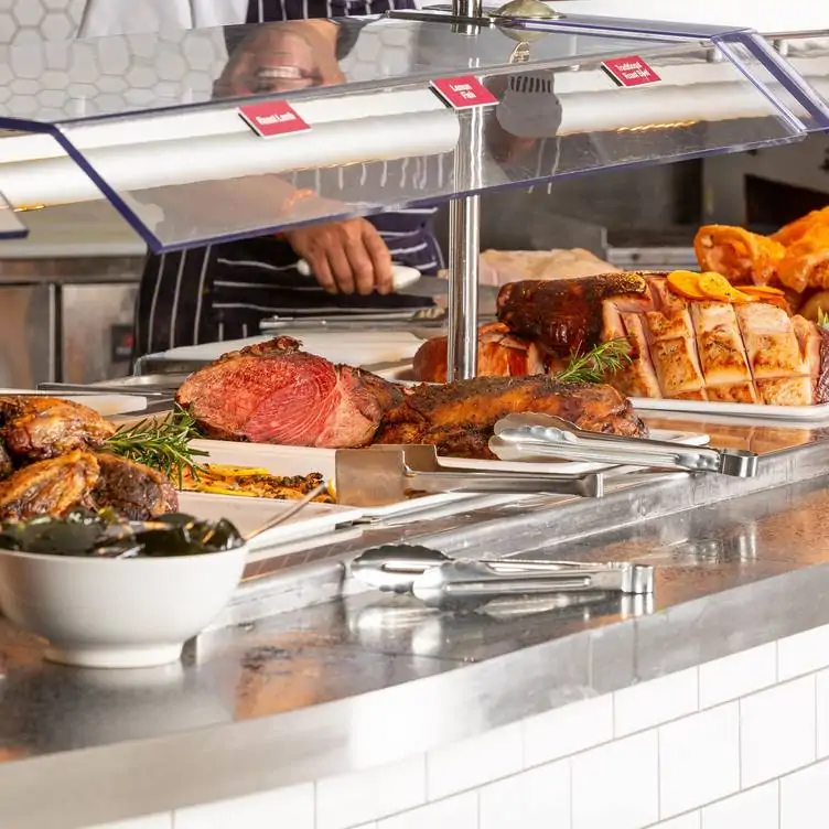 A server stands waiting to carve various types of meat at the buffet meat counter at Braybrook Hotel, one of the best family restaurants in Melbourne.