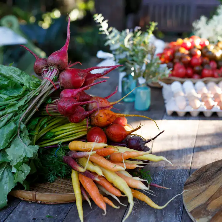 A bunch of root vegetables in front of a table of eggs and fruits at Wild Canary, one of the best family restaurants in Brisbane.