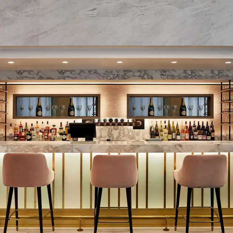 Pale pink cushioned counter chairs at a marble bar at Two 88 Bar and Kitchen, one of the best cocktail bars in Sydney.