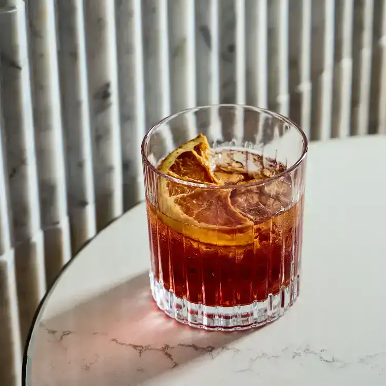 A red-orange cocktail with a lemon slice garnish served at Storehouse Flinders East, one of the best bars in Adelaide.