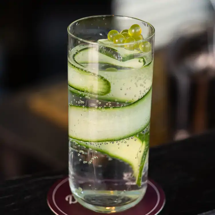 A tall, clear cocktail with a spiral of cucumber served at Dean & Nancy on 22, one of the best cocktail bars in Sydney.