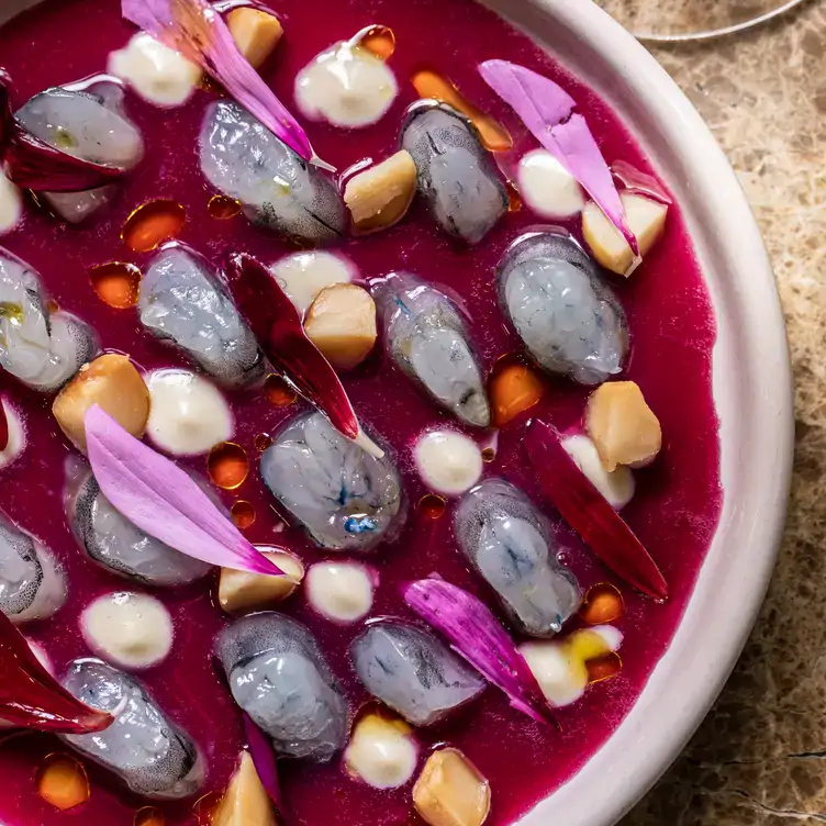 A dish of seafood in a purple sauce, garnished with flowers served at Mode Kitchen & Bar, one of Sydney’s best cocktail bars.