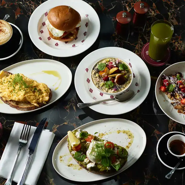 A table with dishes like poached egg on avocado toast, scrambled eggs and porridge served at Dean & Nancy on 22, one of the best cocktail bars in Sydney.