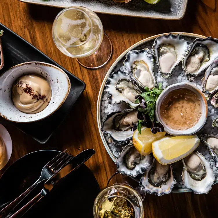 A plate of oysters served alongside some white wine at Grain Bar Sydney, one of the best cocktail bars in Sydney.