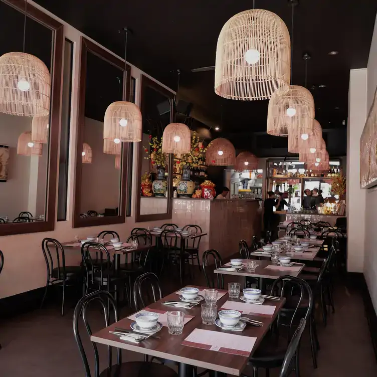 The interior of Ong Vietnamese Kitchen, showing tables filling a long dining space and shaded lights hanging overhead.