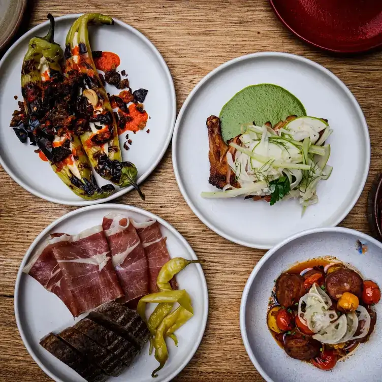 Multiple plates of cured meat, whole peppers and bread served at Udaberri Pintos Y Vino, one of the best wine bars in Adelaide.