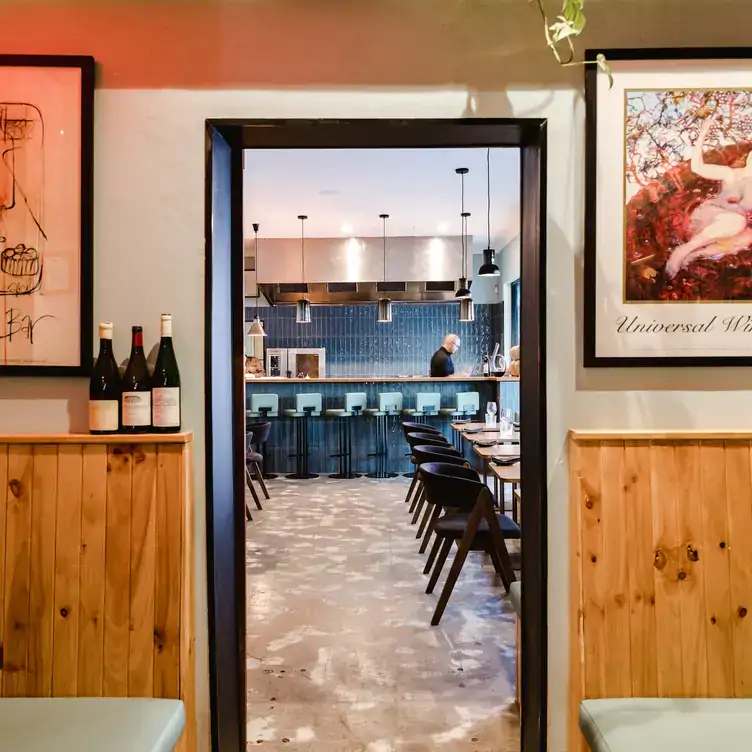 The view from the dining area of Good Gilbert into the front bar area where a bartender stands behind the counter.