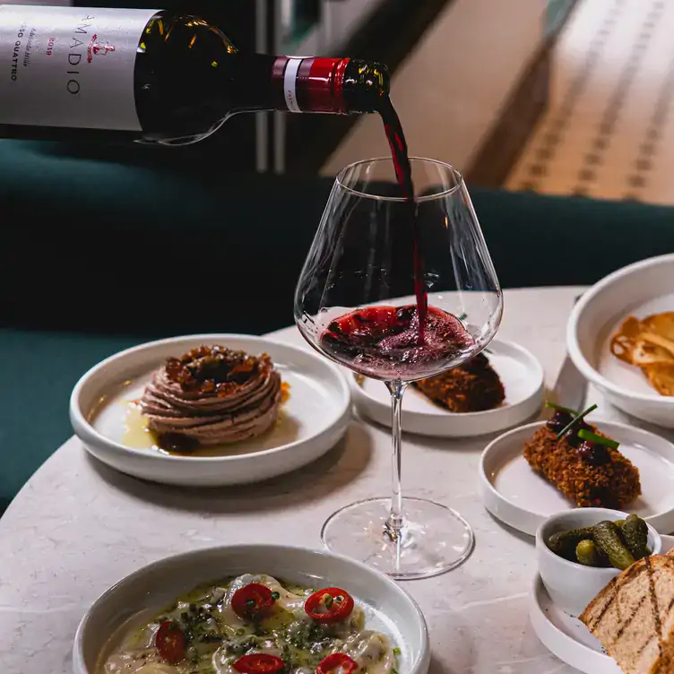 A selection of small plates and a server pouring red wine at South City Wine, one of the best bars in Brisbane