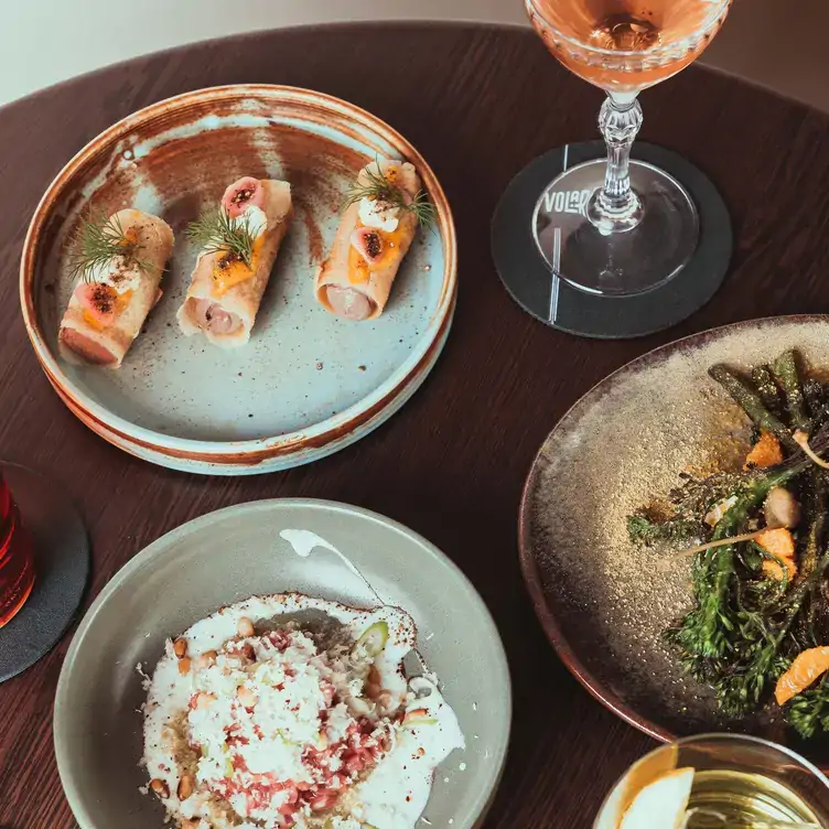 Plates with snacks like sausages and asparagus served alongside drinks at Volare, one of the best bars in Perth.