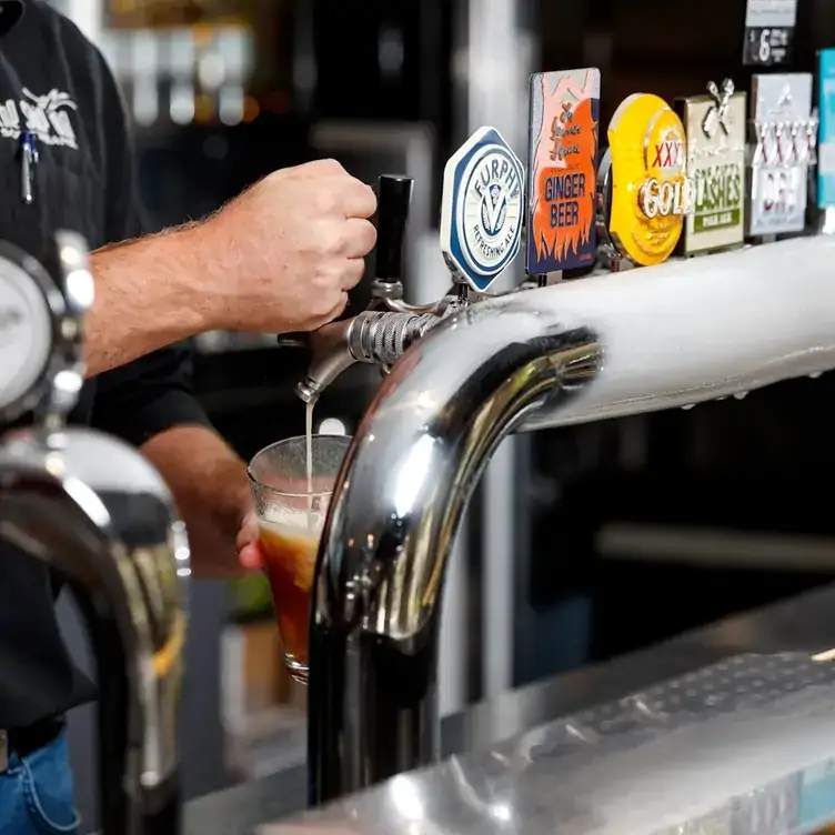 Someone pours a pint of beer from the on-tap options at The Ship Inn, one of Brisbane’s best pubs.