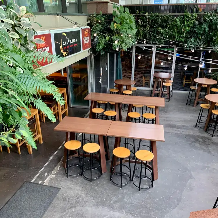 The outdoor seating area at Criterion Tavern, showing the high chairs and tables, and hanging plants and string lights overhead