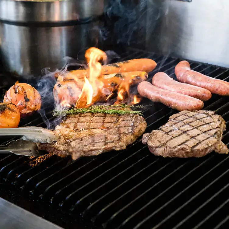 Steak and sausages cooking on the grill at Pacers & Chasers, where you can get one of the best pub lunches in Brisbane.