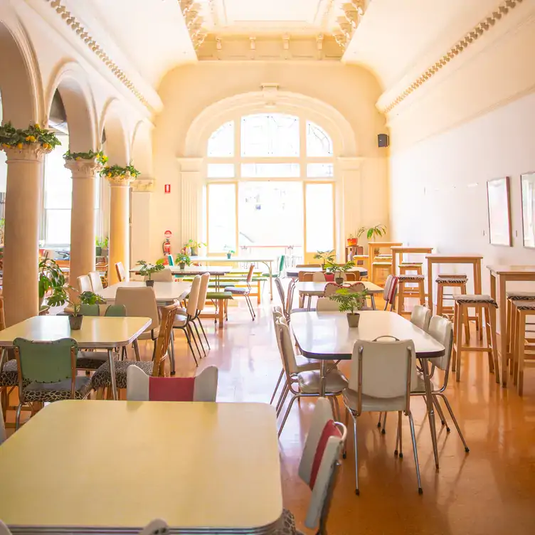 The interior of Two-Bit Villains, showing the archways separating the dining area, a large arched window and relaxed diner-style chairs and tables.